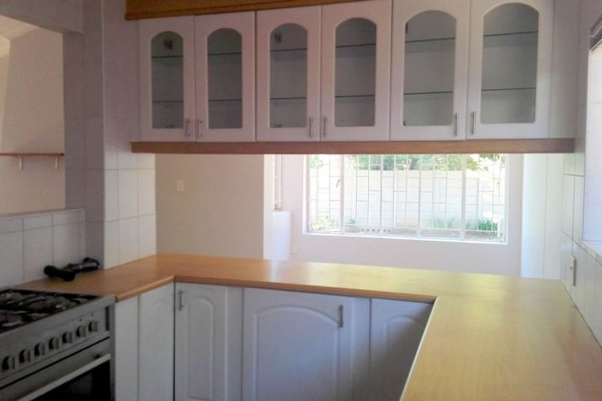 A functional kitchen featuring white cabinetry with glass-fronted uppers, laminate countertops, and a built-in gas stove, offering a clean and practical workspace.