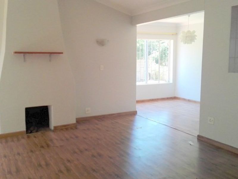 Spacious open-plan living area featuring a fireplace, laminate flooring, and a convenient pass-through window connecting to the kitchen space.