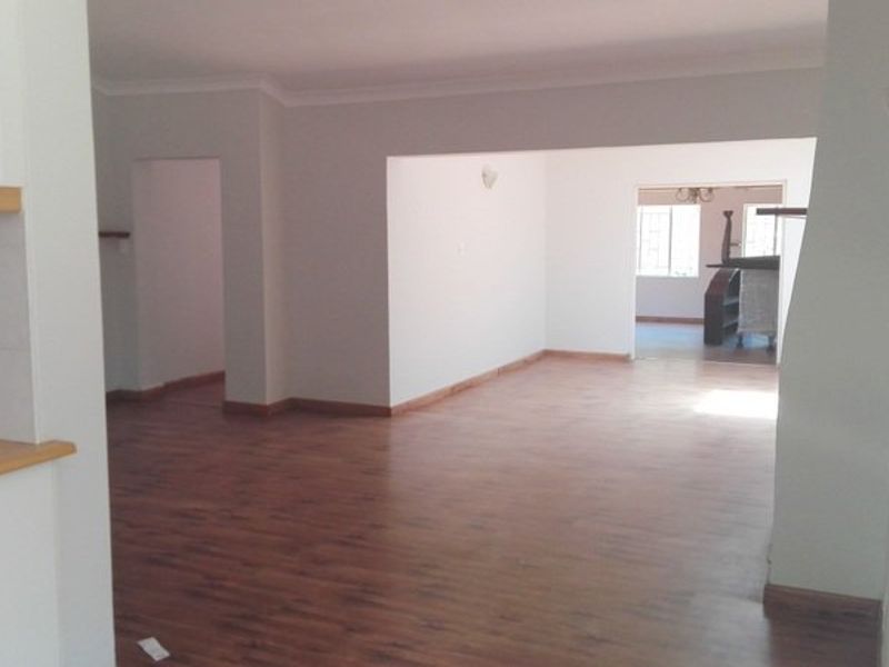 Spacious open-plan living area featuring laminate flooring and neutral walls, offering a versatile layout with seamless flow between connected rooms.