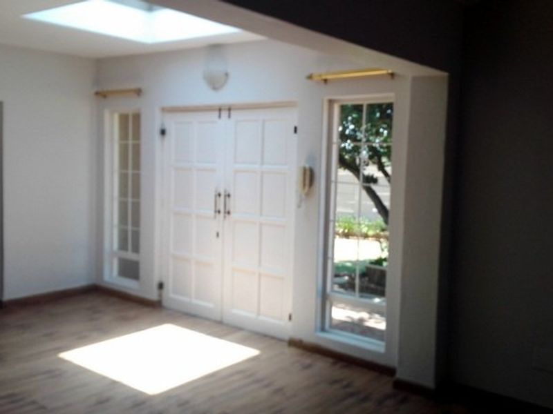 Bright living area featuring laminate flooring, a skylight, and double doors with sidelight windows providing natural light and garden access.
