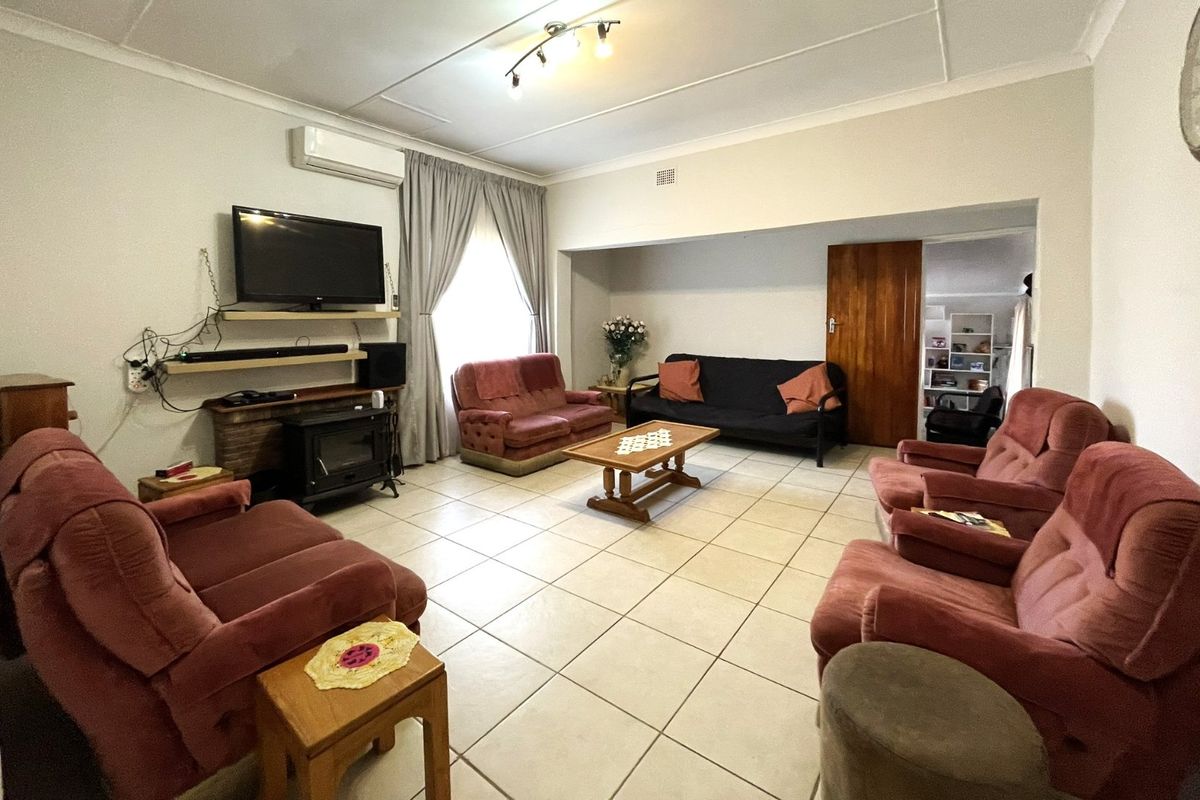 Spacious living room featuring tiled flooring, a wood-burning fireplace, and a wall-mounted air conditioning unit, offering a functional and comfortable family space.