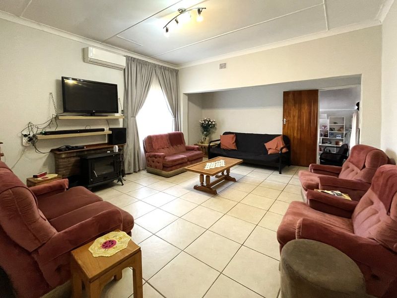 Spacious living room featuring tiled flooring, a wood-burning fireplace, and a wall-mounted air conditioning unit, offering a functional and comfortable family space.