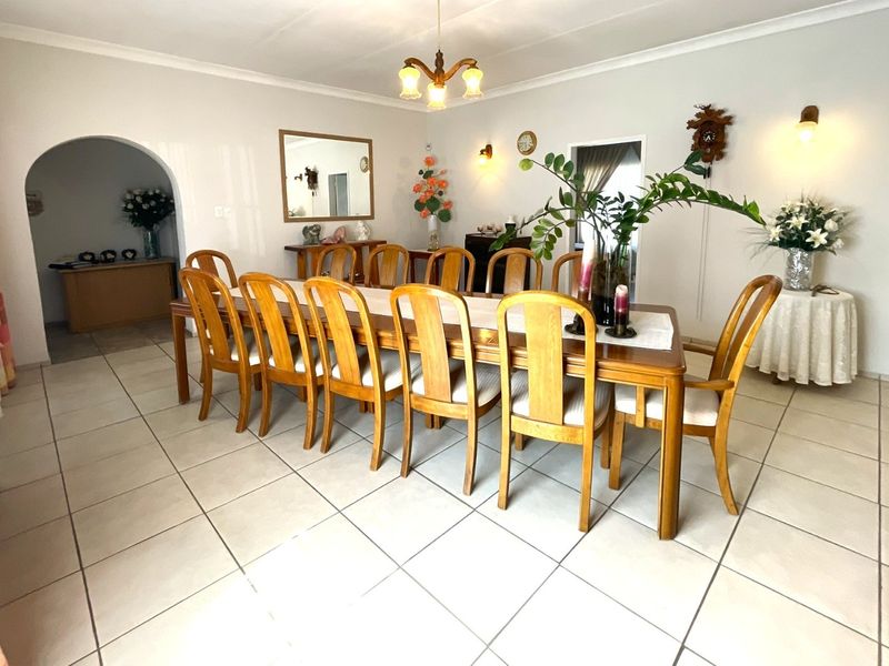 Spacious dining room featuring tiled flooring, a decorative archway, and classic wall sconce lighting, providing a functional area for formal meals.