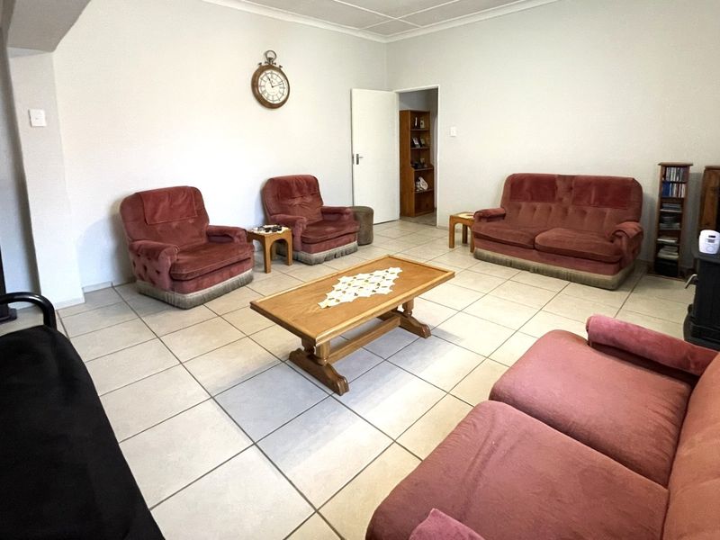 A spacious living room featuring neutral tiled flooring and coved ceilings, providing a functional and well-lit area for relaxation.