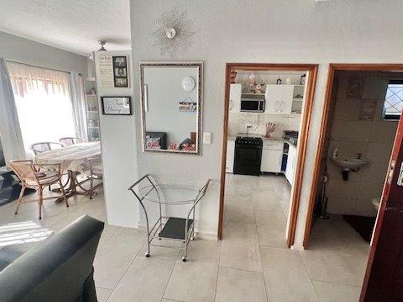 Open plan living area featuring tiled flooring, leading into a functional kitchen and adjacent bathroom space.