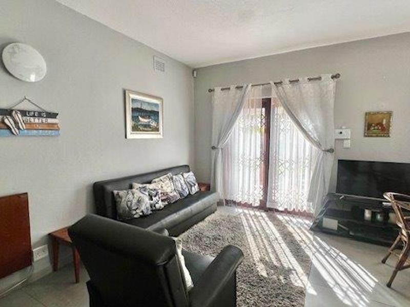 A bright living room featuring tiled flooring and sliding glass doors that provide access to the outdoor area.