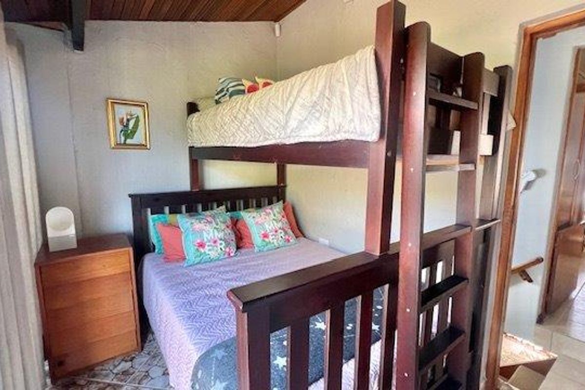A bedroom featuring a wooden bunk bed, tiled flooring, and a timber-clad ceiling, with an adjacent hallway visible.