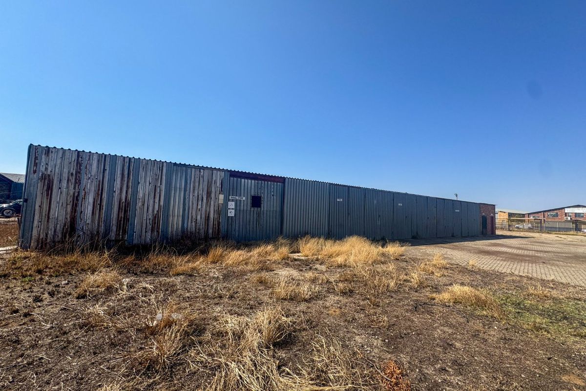 Exterior view of an industrial storage facility featuring corrugated metal cladding with visible signs of weathering and rust, set on a paved lot.