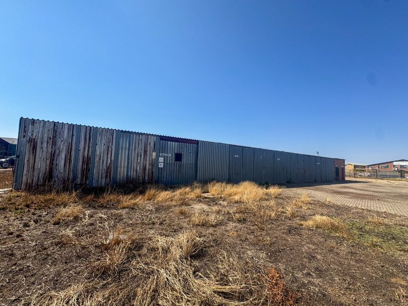 Exterior view of an industrial storage facility featuring corrugated metal cladding with visible signs of weathering and rust, set on a paved lot.