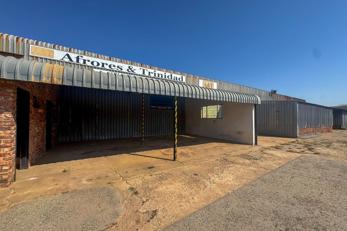 Industrial property exterior featuring corrugated metal roofing, brick masonry walls, and a concrete apron entrance area.
