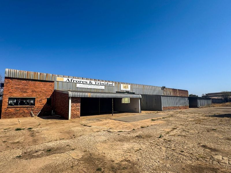 Industrial warehouse facility featuring a combination of face brick and corrugated metal cladding with a large concrete apron and covered loading area.