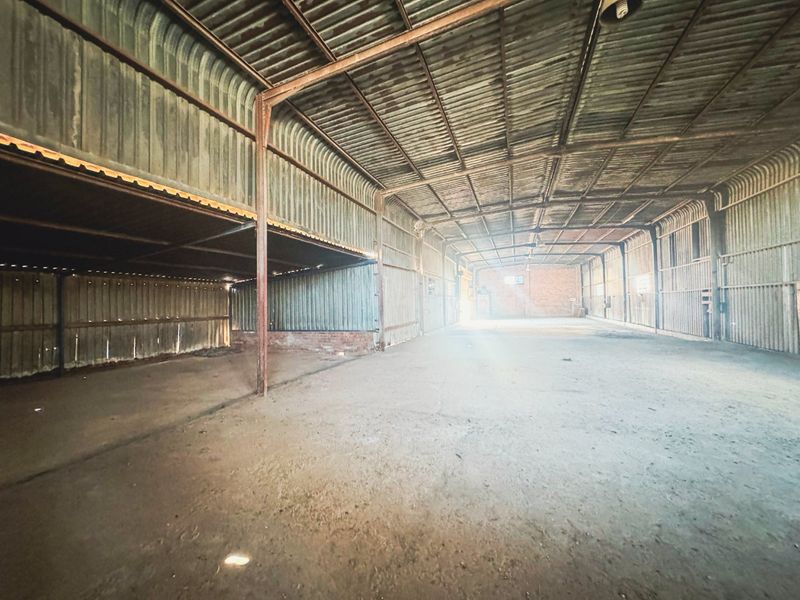 A large, open-plan industrial utility space featuring corrugated metal walls, exposed steel structural framing, and a concrete floor.