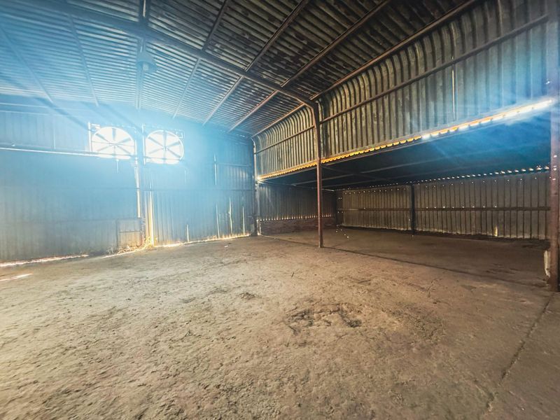 Spacious industrial utility area featuring a steel frame structure, corrugated metal walls, concrete flooring, and integrated industrial exhaust fans.