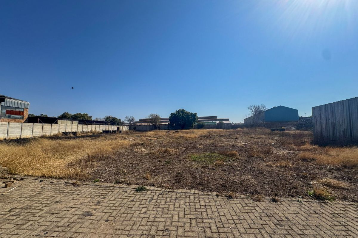 Expansive industrial plot featuring a paved entrance area, enclosed by precast concrete and corrugated metal boundary walls, offering significant development potential.