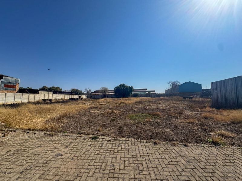 Expansive industrial plot featuring a paved entrance area, enclosed by precast concrete and corrugated metal boundary walls, offering significant development potential.