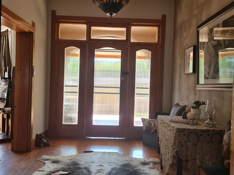 A welcoming entrance hall featuring original timber flooring, ornate pressed metal ceilings, and classic timber-framed doors with ribbed glass panels.