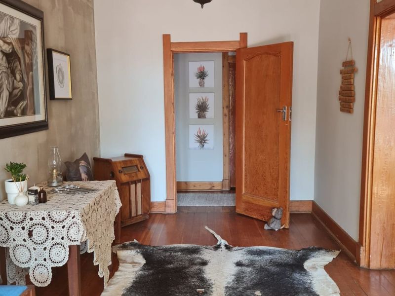 A well-maintained hallway featuring original hardwood flooring, ornate ceiling detailing, and classic timber door frames leading to adjacent rooms.