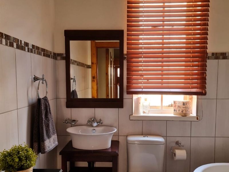 A well-maintained bathroom featuring a vessel sink, a freestanding bathtub, and tiled walls with decorative border accents.