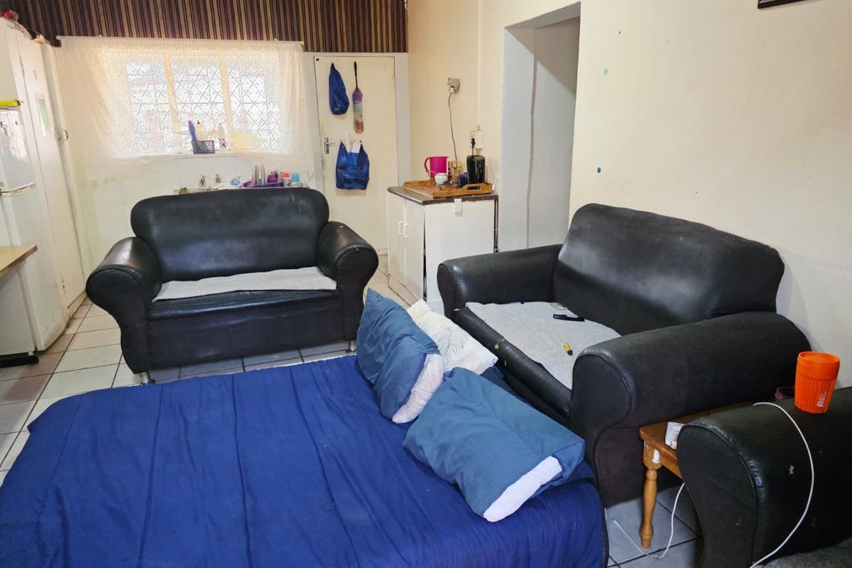 A living area featuring tiled flooring and a window with security bars, requiring cosmetic updates to improve the overall condition of the wall finishes.