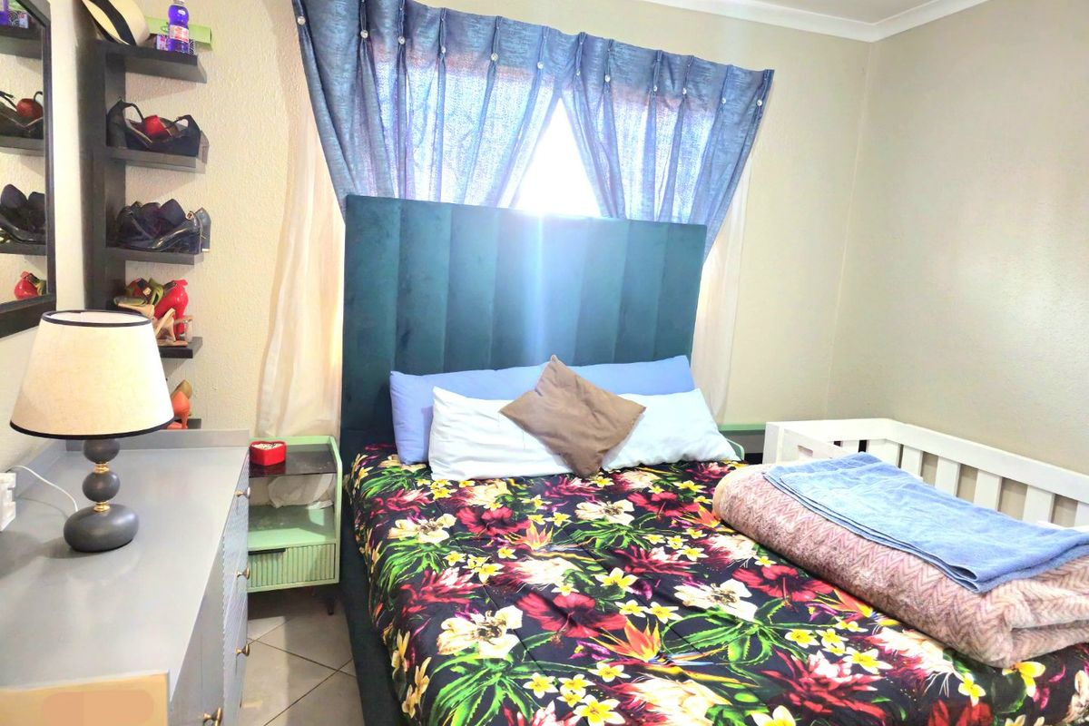 A bedroom featuring tiled flooring and built-in shelving, providing a functional space with neutral wall finishes.