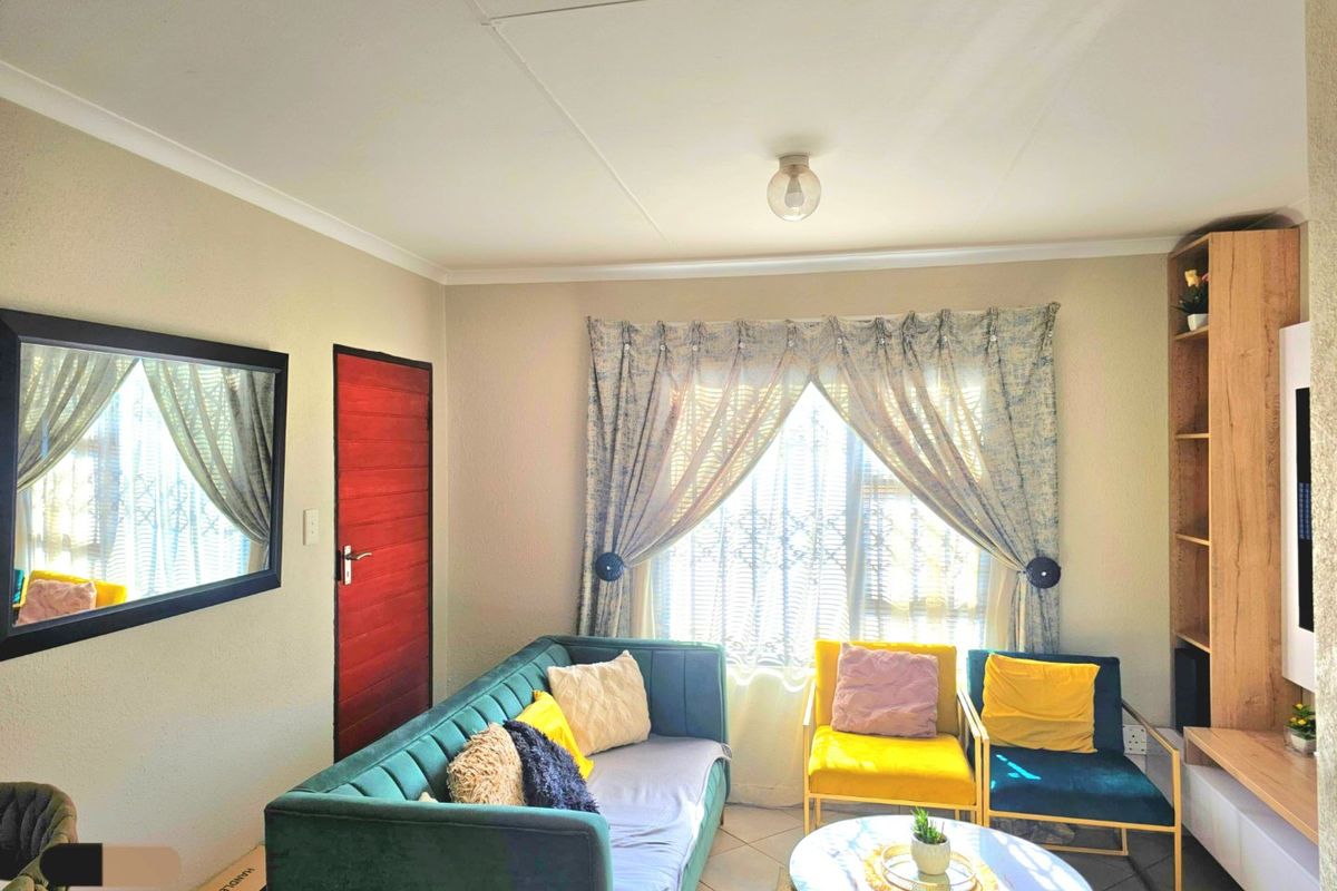 A cozy living room featuring tiled flooring, a built-in shelving unit, and a window fitted with a security gate.
