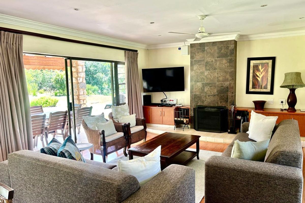 Spacious living room featuring a tiled fireplace, ceiling fan, and large sliding glass doors providing direct access to the outdoor patio area.