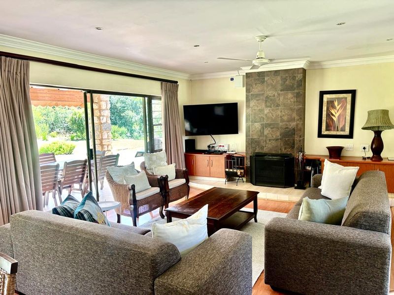 Spacious living room featuring a tiled fireplace, ceiling fan, and large sliding glass doors providing direct access to the outdoor patio area.