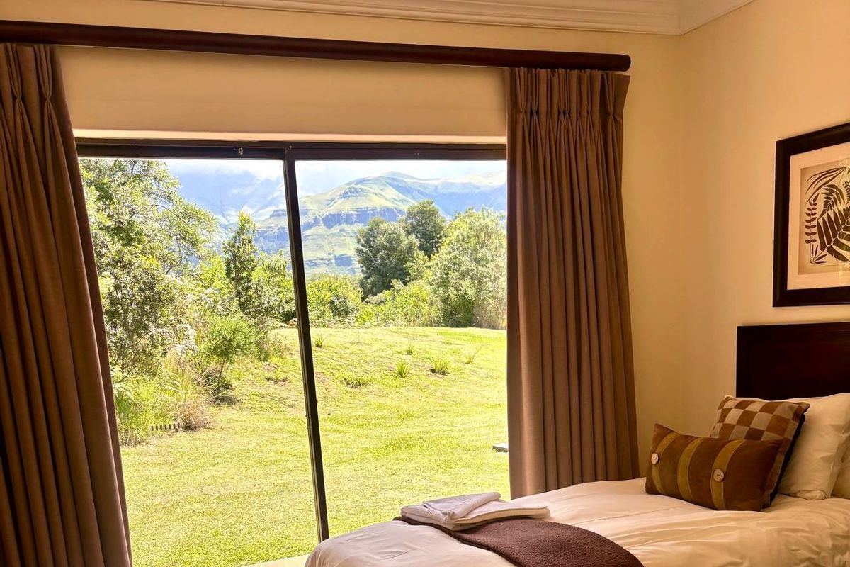 A well-maintained bedroom featuring a large sliding glass door that provides direct access to the garden and scenic mountain views.