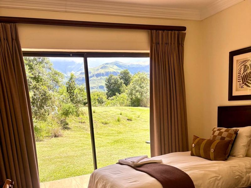 A well-maintained bedroom featuring a large sliding glass door that provides direct access to the garden and scenic mountain views.