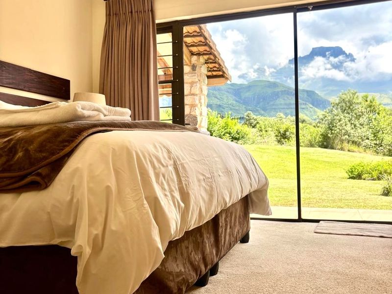 A well-maintained bedroom featuring large sliding glass doors that provide expansive mountain views and direct access to the garden.