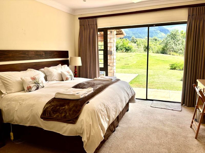 Spacious bedroom featuring neutral carpeting, coving, and large sliding glass doors that provide direct access to the garden and scenic mountain views.
