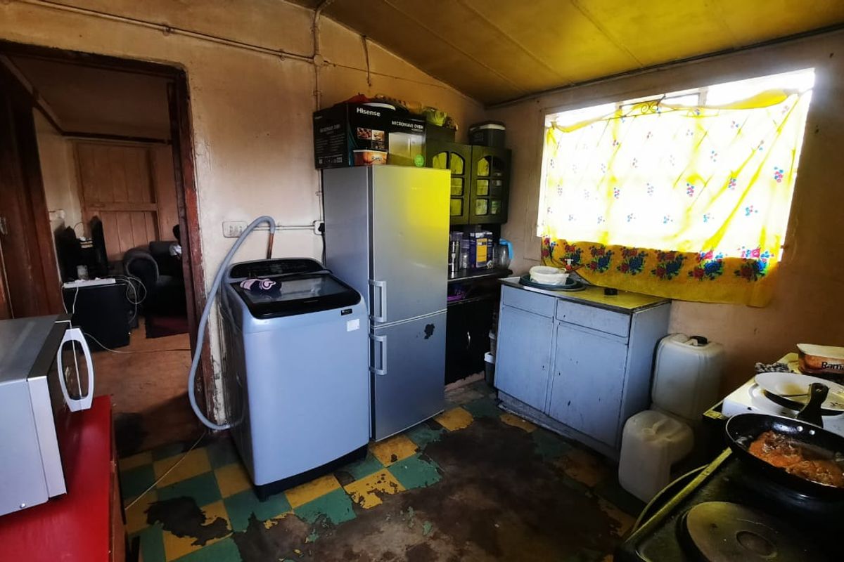 A dated kitchen area featuring basic cabinetry, a sink, and an electric stove, requiring significant renovation and cosmetic updates to improve functionality and aesthetic appeal.
