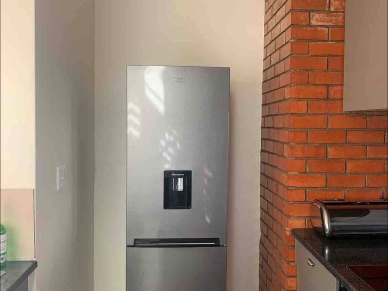 A kitchen area featuring an exposed brick pillar, tiled flooring, and modern cabinetry with granite countertops.