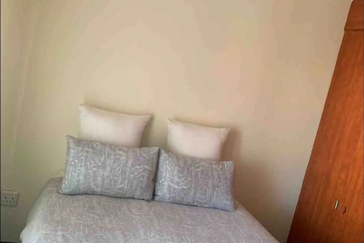A bedroom featuring a built-in wooden wardrobe and neutral wall finishes.