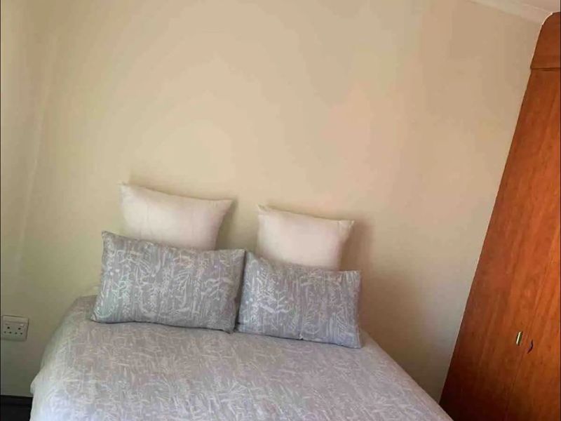 A bedroom featuring a built-in wooden wardrobe and neutral wall finishes.