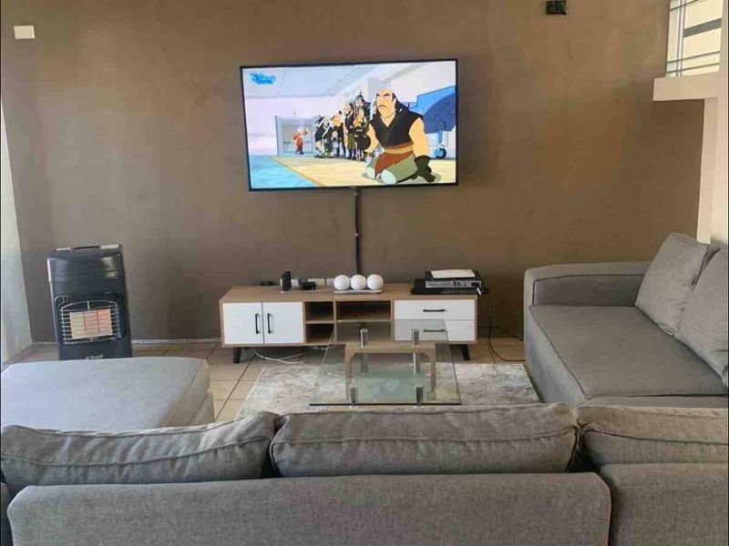 A comfortable living room featuring tiled flooring and a neutral accent wall, providing a functional space for relaxation and entertainment.