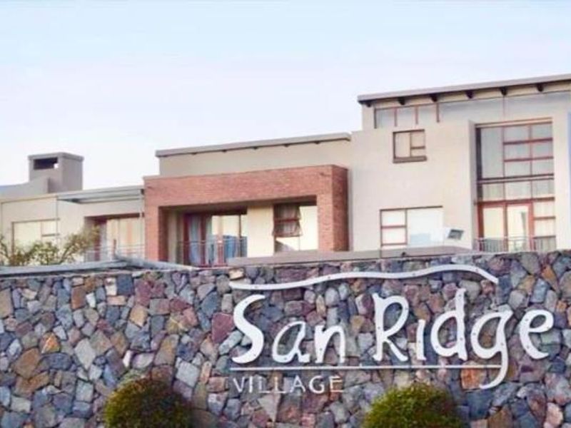 Front elevation of San Ridge Village apartment complex featuring modern architectural design with stone cladding and large windows.