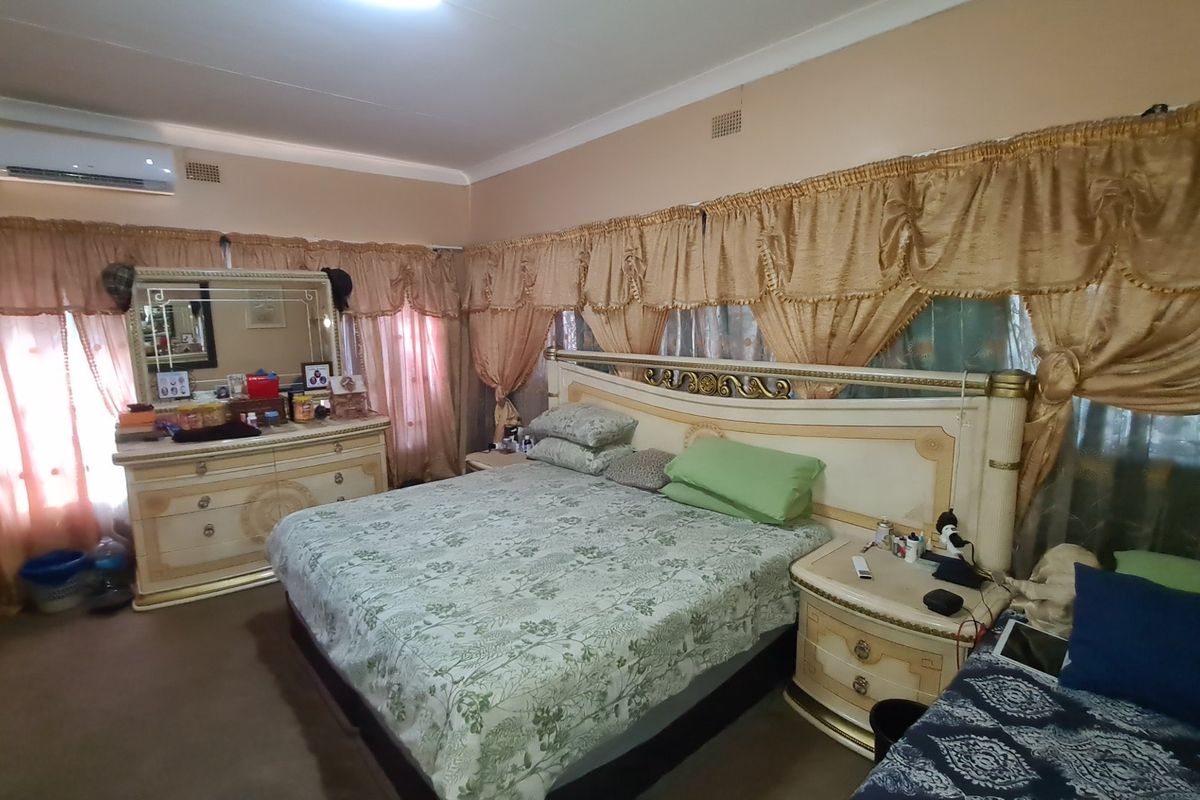 A spacious bedroom featuring a wall-mounted air conditioning unit, built-in cabinetry, and neutral wall finishes.