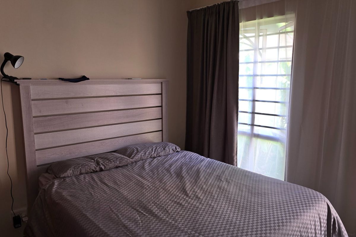 A bedroom featuring a window with fitted curtains and neutral wall finishes.