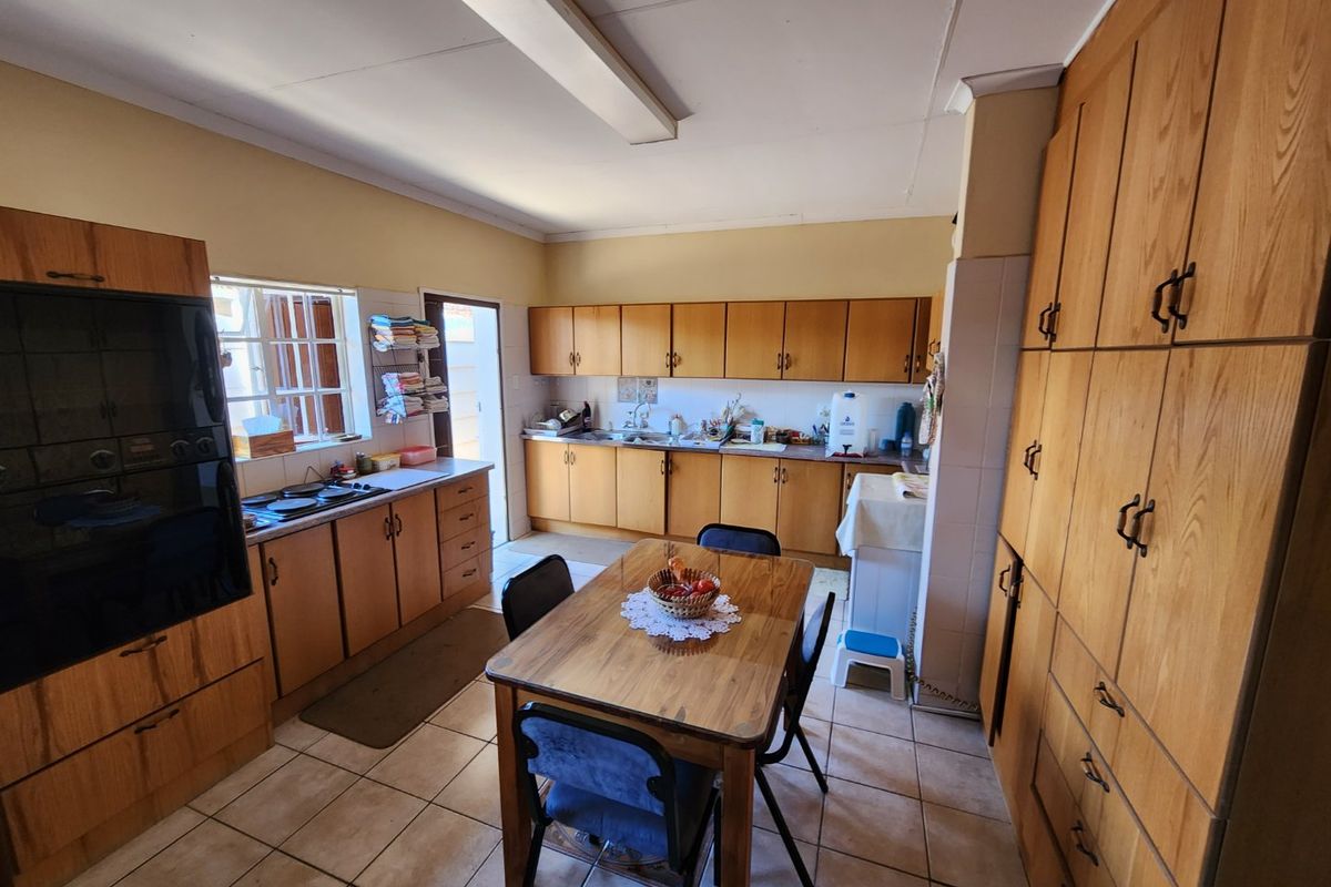A spacious kitchen featuring extensive wooden cabinetry, integrated oven, hob, and tiled flooring, offering a functional layout with ample storage space.