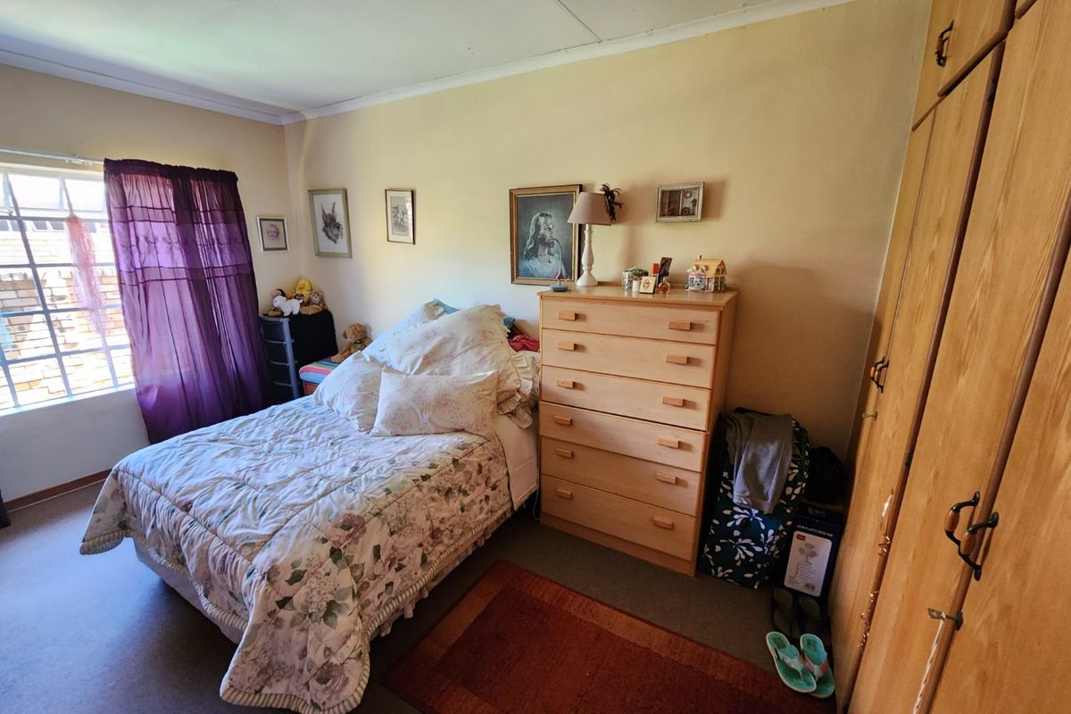 A bedroom featuring built-in wooden cupboards and a window with natural light.
