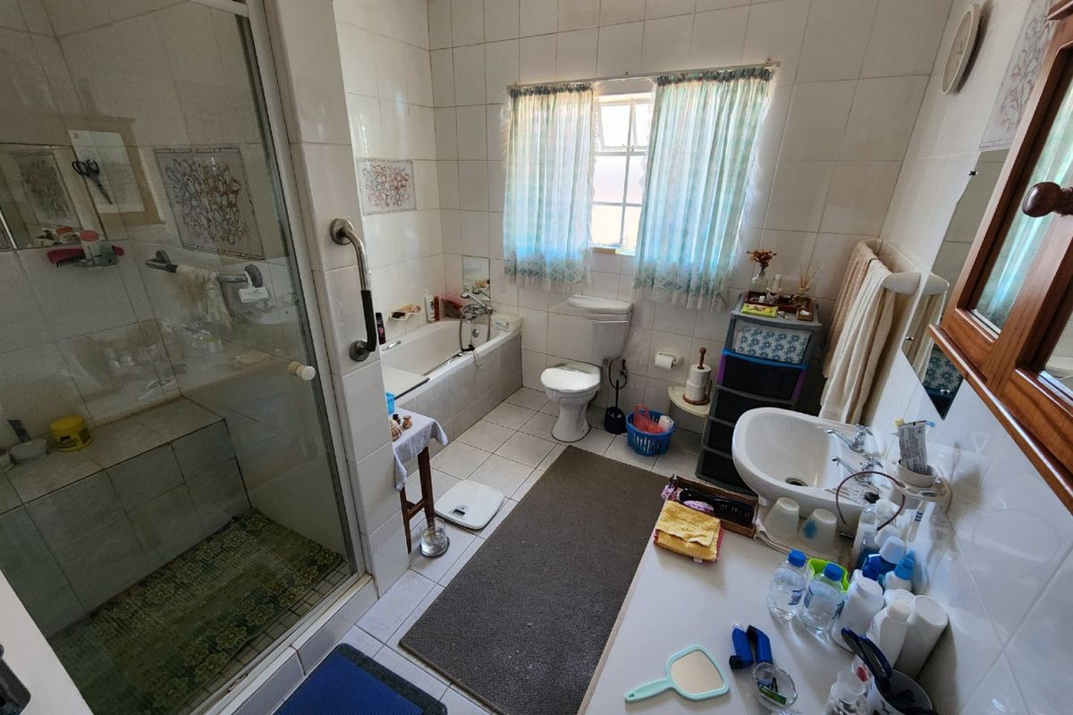 A functional bathroom featuring a separate shower enclosure, built-in bathtub, pedestal basin, and toilet, finished with full-height wall tiling.