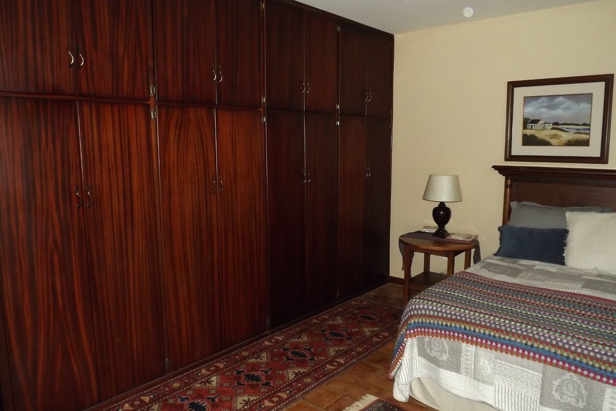 A bedroom featuring extensive floor-to-ceiling built-in wooden cabinetry and tiled flooring, offering ample storage space.
