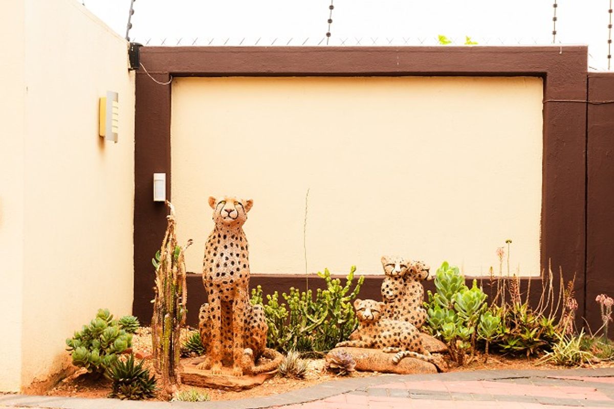 A secure rear courtyard area featuring a high perimeter wall with integrated electric fencing and wall-mounted lighting fixtures.
