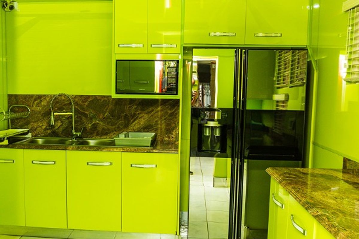 A vibrant kitchen featuring high-gloss lime green cabinetry, granite countertops, a double basin sink, and integrated appliances including a large side-by-side refrigerator.