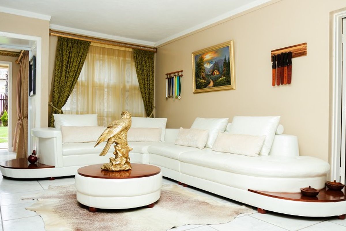 A living room featuring tiled flooring and neutral wall tones, providing a functional space with access to adjacent areas.