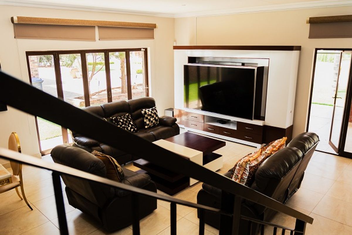 Spacious living room featuring a large built-in media unit, tiled flooring, and bi-fold doors providing direct access to the outdoor area.