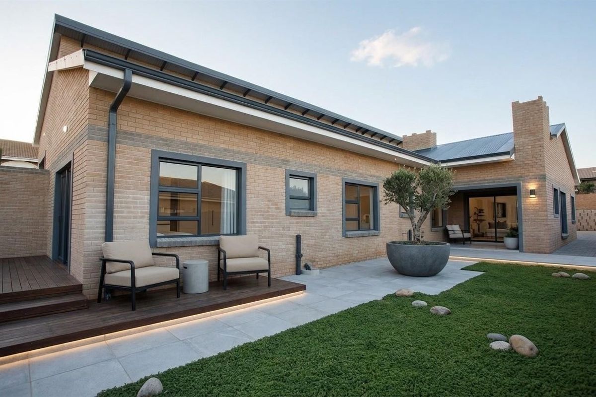 Modern rear exterior featuring face brick walls, timber decking with integrated LED lighting, paved patio area, and large sliding glass doors.