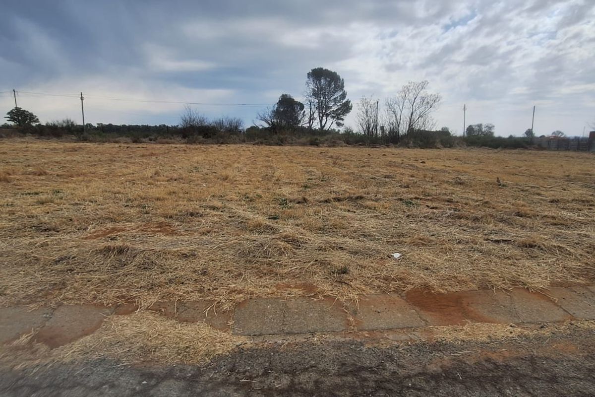 A vacant residential plot of land featuring dry grass, level terrain, and surrounding boundary fencing, offering a blank canvas for new construction.