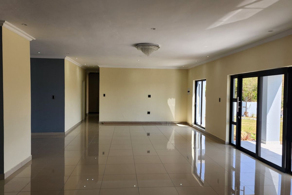 A spacious, open-plan living area featuring polished porcelain floor tiles, recessed lighting, and large aluminium sliding doors providing access to the exterior.